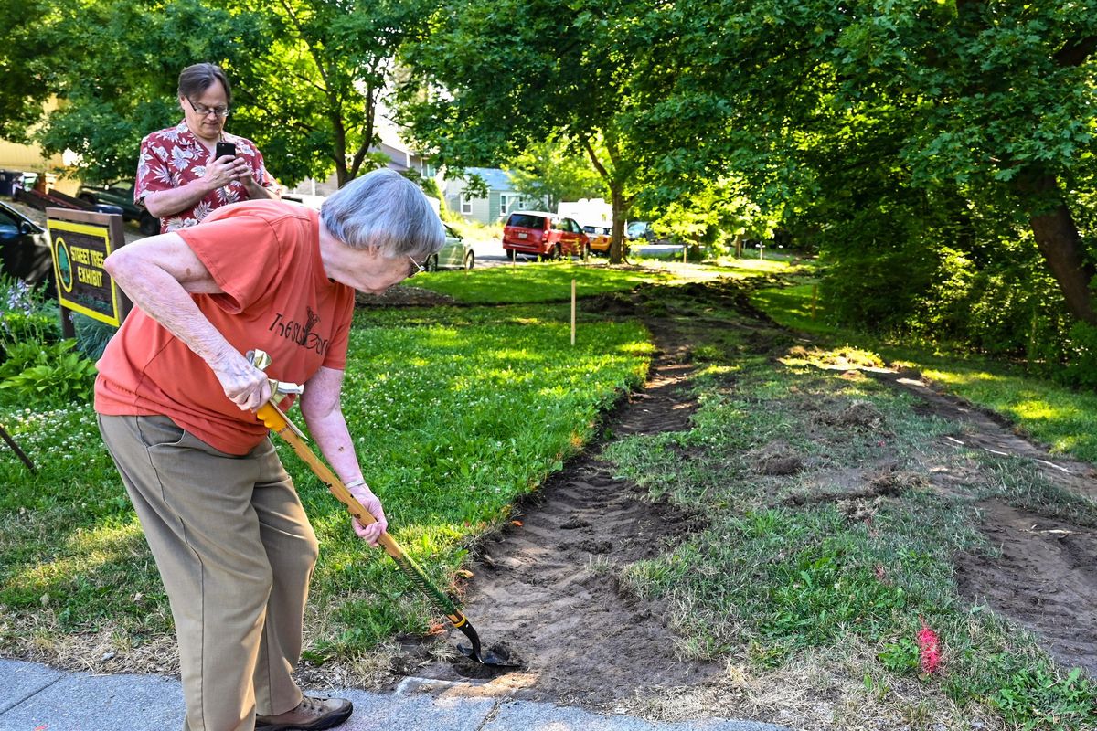 Nancy MacKerrow takes a ceremonial shovel of dirt for the new Susie Stephens Trail on Wednesday at the corner of Woodland Boulevard and D Street in Spokane. Her son, Jack Stephens, is taking cell phone pictures.  (DAN PELLE/THE SPOKESMAN-REVIEW)