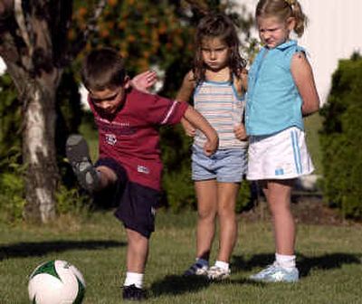 Abby Nurvic, 5, center, and Brittney Presley, 6, watch as Mathew Pixley, 4, completes a kicking drill on Upward Soccer evaluation night at the Valley Open Bible Church. 
 (Liz Kishimoto / The Spokesman-Review)
