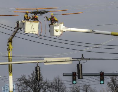 In this Thursday, Dec. 14, 2017 photo, Owensboro Municipal Utilities line workers Michael Atherton, from left, Sean Warren and Lee Broadley work to remove temporary line switches from power lines at the intersection over Ninth Street and J. R. Miller Boulevard in Owensboro, Ky. (Greg Eans / Associated Press)