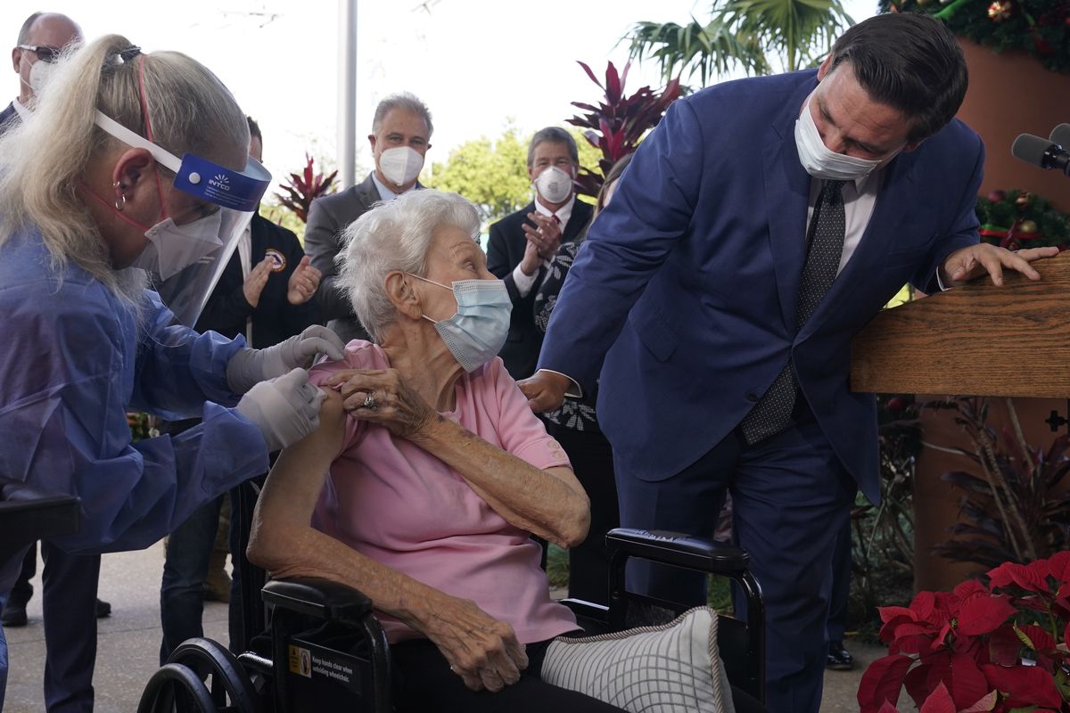 FILE - In this Dec. 16, 2020, file photo, Florida Gov. Ron DeSantis asks Vera Leip, 88, how she feels after nurse Christine Philips, left, administered the Pfizer vaccine at John Knox Village, in Pompano Beach, Fla. DeSantis is walking back his claims that his state has now vaccinated 1 million seniors. State officials acknowledged that it could take a few more days to reach the milestone.  (Marta Lavandier)