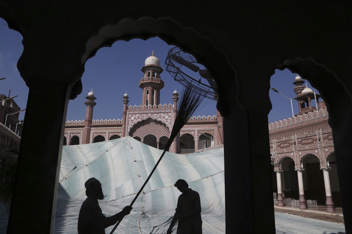 FILE - In this, Friday, April 9, 2021, file photo, volunteers clean the outer areas of the historic Mohabat Khan Mosque ahead of the upcoming Muslim fasting month of Ramadan, in Peshawar, Pakistan. Muslims are facing their second Ramadan in the shadow of the pandemic. Many Muslim majority countries have been hit by an intense new coronavirus wave. While some countries imposed new Ramadan restrictions, concern is high that the month’s rituals could stoke a further surge.  (Muhammad Sajjad)