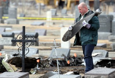 A worker carries a piece of propeller Tuesday as NTSB investigators and local authorities scour the scene at Holy Cross Cemetery, scene of the fatal plane crash  that killed 14 Sunday.  (Associated Press / The Spokesman-Review)