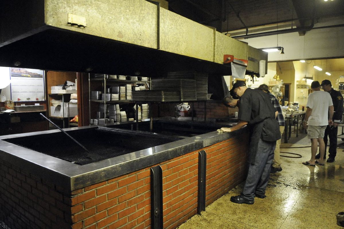 Longhorn Barbecue employees wipe down the pit area where a couple of pigs were cooking Saturday night and caused smoke to fill the restaurant, Sept. 11, 2010 in Spokane Valley, Wash. (Dan Pelle)