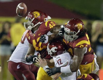 Southern California defensive end Leonard Williams, right, and linebacker Devon Kennard force a fumble by Washington State quarterback Connor Halliday during the first half at the Los Angeles Coliseum Saturday evening. (Associated Press)