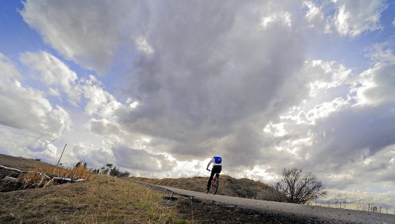 Lauri Costello fights a headwind as she rides through Moran Prairie on the old Ben Burr rail line trail Thursday March 24, 2011. Costello was headed to Tower Mountain and back before those black clouds could dump any more rain on the Spokane, Wash. area.  (Christopher Anderson)