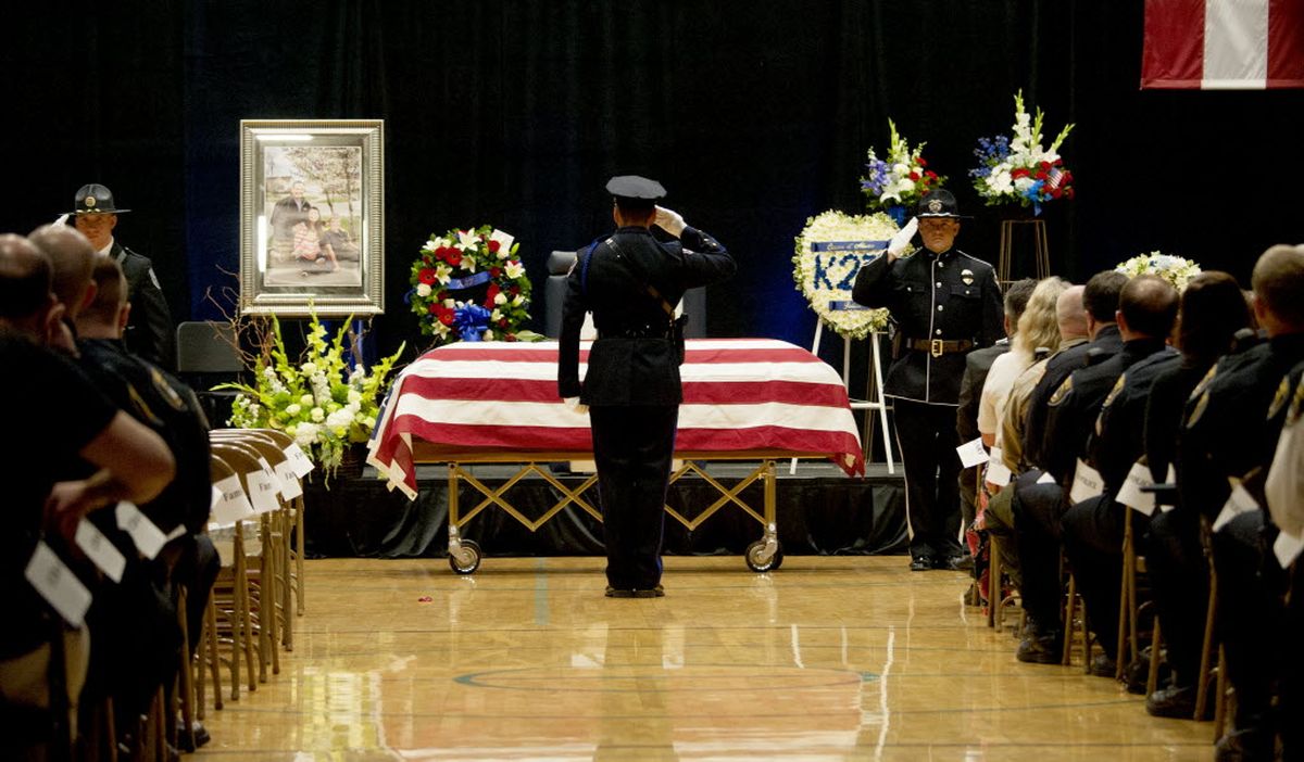 An officer salutes the flag draped coffin the funeral service at Lake City High School today ... (Kathy Plonka)