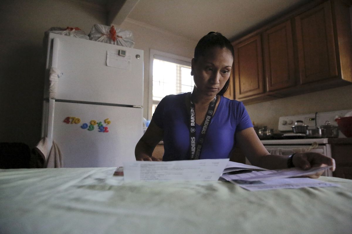 Mary Taboniar, a housekeeper at the Hilton Hawaiian Village resort in Honolulu, looks over bills at her home Saturday in Waipahu, Hawaii. Taboniar went 15 months without a paycheck due to the COVID pandemic. The single mother of two saw her income completely vanish as the virus devastated the hospitality industry. Taboniar is one of millions of Americans for whom Labor Day 2021 represents a perilous crossroads.  (Caleb Jones)