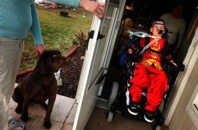 
Zak Baldwin, 8, rolls out of his Airway Heights home while his mother, Liz, holds the door and the family's dog on Wednesday. Baldwin was hit by a car on his dirt bike last summer. 
 (Jed Conklin / The Spokesman-Review)