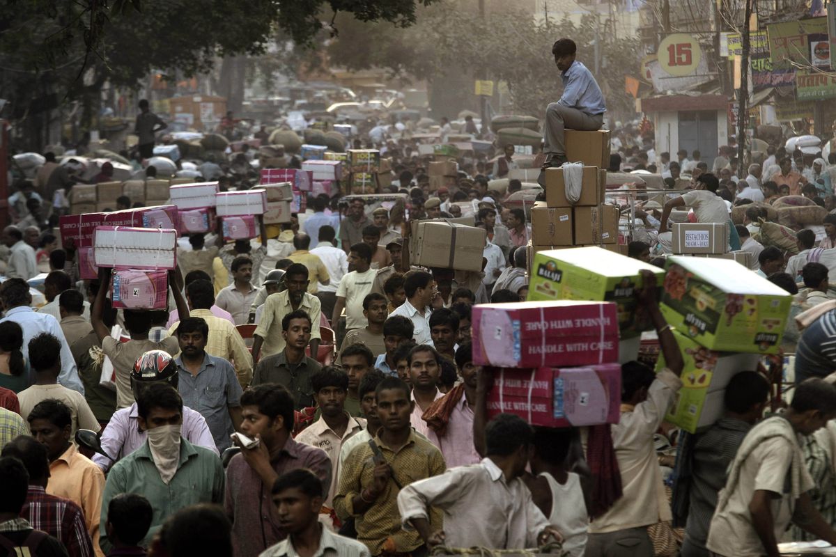 A shopkeeper sits on boxes as he waits for transportation at a busy wholesale market in New Delhi in October. (Associated Press)