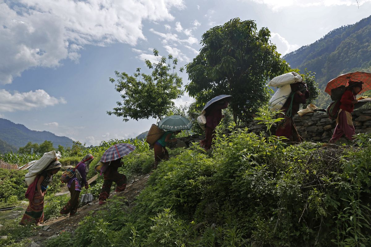Villagers start their 12 mile-hike back up to their mountain home with international relief aid they received in the damaged village of Balua, Nepal, on Thursday. (Associated Press)