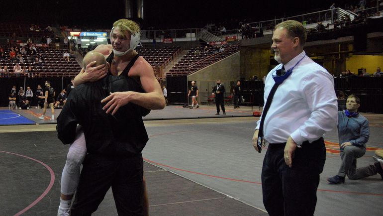 Coeur d’Alene junior Gunner Giulio celebrates his third consecutive 5A state title with his coaches. Giulio earned a 5-3 decision over Kuna’s Dante Roggio in the 170-pound final. (Joe Jaszewski)