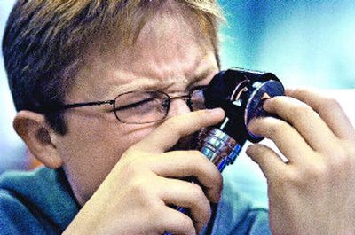 
Brentwood Elementary fourth-grader Josh Everett scrunches up his face Tuesday as he uses an illuminated magnifying scope to look at rocks.
 (Christopher Anderson / The Spokesman-Review)