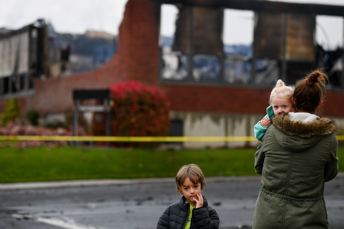 Theresa Carstensen holds her daughter Blair, 2, as her son Brock, 6, turns away, as the trio takes in what is left of the Almira School on Wednesday after the school burned Tuesday night in Almira, Wash.  (Tyler Tjomsland/The Spokesman-Review)