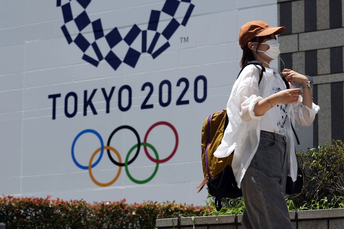 In this Tuesday, July 20, 2021, file photo, a woman wearing a protective mask walks in front of a Tokyo 2020 Summer Olympics display at the Tokyo Metropolitan government in Tokyo. The Tokyo Olympics have already broken new ground because of the 12-month delay caused by the coronavirus pandemic, pushing it into an odd-numbered year for the first time. But with no fans permitted in Japan, foreign or local, it has the undesirable distinction of being the first Games to be held with no spectators.  (Associated Press)