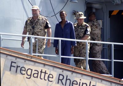 German military personnel escort one of seven suspected Somali pirates, on board the German frigate Rheinland-Pfalz, before handing them over to authorities in Mombasa, Kenya, on Wednesday. The alleged Somali pirates were held aboard the German frigate Rheinland-Pfalz, after the seven apparently mistook the FGS Spessart for a commercial ship and opened fire on March 29. They were chased down and captured by international forces.  (Associated Press / The Spokesman-Review)