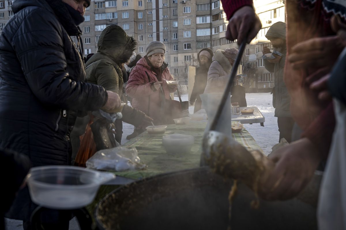 People eat soup at a free outdoor kitchen amid power cuts and freezing temperatures on Feb. 1 in Kyiv, Ukraine. As more peace talks are scheduled later this week, Ukrainian officials say the Trump administration is ramping up pressure on them to make concessions to Russia in a push to end the war by early summer.  (Lynsey Addario/The New York Times)