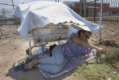 
Lesleejo Ruther, 47, takes refuge Wednesday from the sun under a blanket on her shopping cart during Phoenix's record heat wave.
 (Associated Press / The Spokesman-Review)