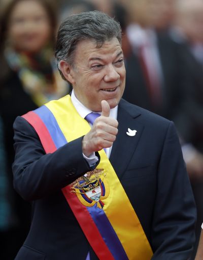 Wearing the presidential sash, newly sworn-in President Juan Manuel Santos flashes a thumbs-up during his inauguration ceremony Thursday in Bogota, Colombia. (Associated Press)
