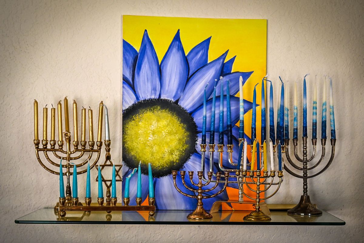 Sharon Moses gathers some of her menorah collection on a shelf with a painting by her granddaughter.  (DAN PELLE/THE SPOKESMAN-REVIEW)