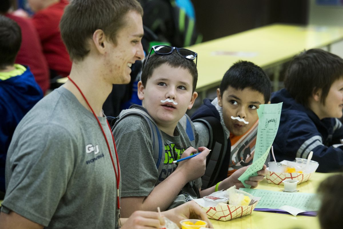 Shiloh Hills Elementary School students Jack Driscoll, Abinam Giri and Jace Tinney, right, share breakfast time with Gonzaga University student-athlete Carsten Beckwith during National Breakfast Week activities Friday at the north Spokane school. Beckwith, a member of the GU rowing team, along with other GU athletes, mingled with the Shiloh Hills students before the start of classes. (PHOTOS BY DAN PELLE)