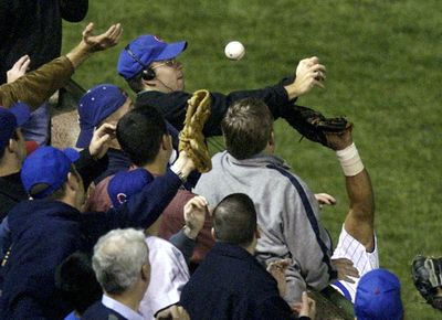 ** RETRANSMITTED TO ADD DATE OF BASEBALL AUCTION ** FILE ** Chicago Cubs left fielder Moises Alou's arm is seen reaching into the stands, at right, unsuccessfully for a foul ball against the Florida Marlins, as fan Steve Bartman deflects the ball, at top, in the eighth inning during Game 6 of the National League championship series in this Oct. 14, 2003 file photo, at Wrigley Field in Chicago. The baseball in the infamous