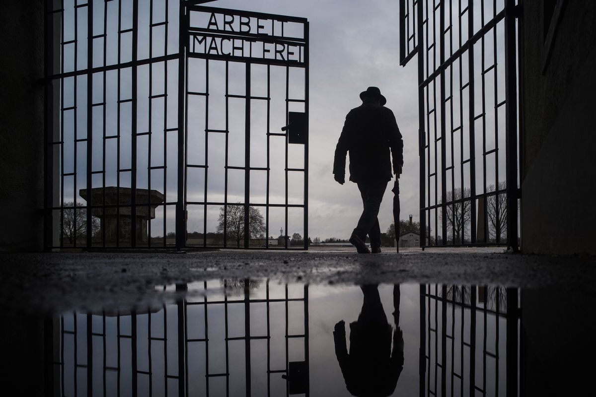 In this Sunday, Jan. 27, 2019 photo, a man walks through the gate of the Sachsenhausen Nazi death camp with the phrase 