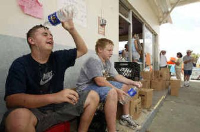 
Casey Flinn, 16, left, of Cape Coral, Fla., cools himself off alongside R.J. Levasseur, 15, as the two volunteer Thursday at the Convoy of Hope in Punta Gorda, Fla. 
 (Associated Press / The Spokesman-Review)