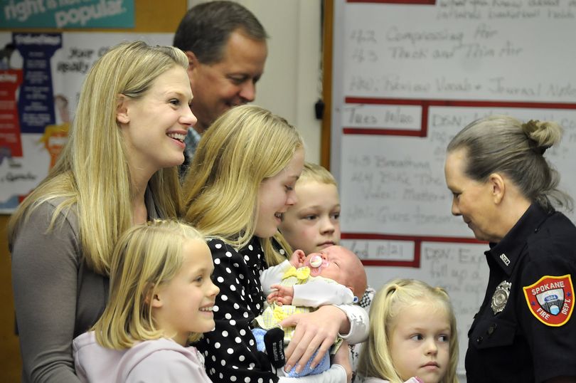 Emma Herb ( center in polka dots ) holds her newborn  sister Hadley as her family gathers for a photo with Spokane FIre Department dispatcher Linda Hendrix ( far right ) Monday, October 26, 2009.  The Fire Department came to Sacajawea Middle School to give Emma recognition for calling 911 and relaying instructions from Hendrix to the rest of the family when her mother Amanda ( far left ) went into delivery unexpectedly.  CHRISTOPHER ANDERSON chrisa@spokesman.com (Christopher Anderson / The Spokesman-Review)