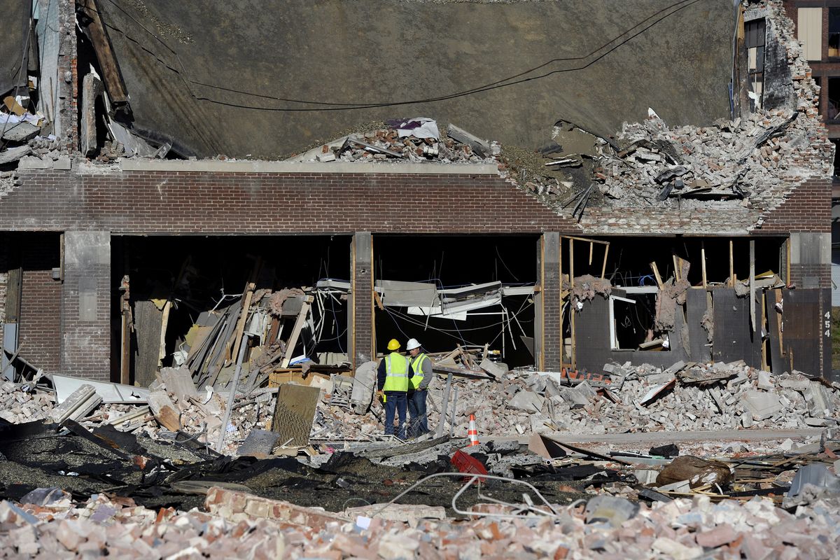 Inspectors stand in debris, Saturday, Nov. 24, 2012, at the site of a gas explosion that leveled a strip club in Springfield, Mass., on Friday evening. Investigators were trying to figure out what caused the blast where the multistory brick building housing Scores Gentleman