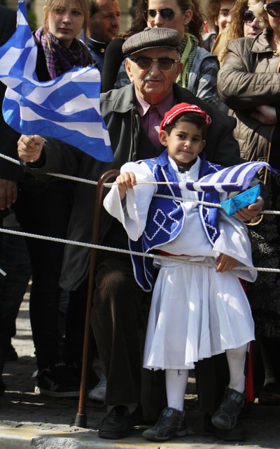 A grandfather and  his grandson hold Greek flags during a military parade in Athens on Thursday. Greece is celebrating its independence frugally – without tanks and jets – because of its acute financial crisis.  (Associated Press)