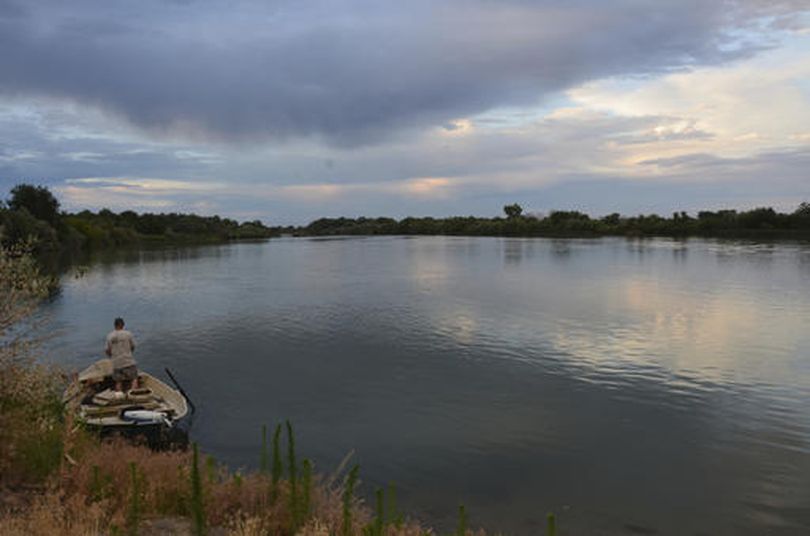 In this Sept. 25, 2014, file photo, a fisherman stands in his boat looking across the Snake River near Homedale, Idaho. Federal officials say changes in how dams on the Snake and Columbia rivers are operated are needed to improve migratory conditions for protected runs of Snake River chinook salmon and steelhead. (Roger Phillips /Idaho Statesman via AP, File) (AP/Idaho Statesman / Roger Phillips)