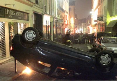 
Protesters stand near an overturned car during clashes in the street Thursday near the Sorbonne University, following a student protest against the new First Job Contract, known as CPE. 
 (Associated Press / The Spokesman-Review)