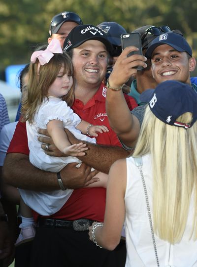 Patrick Reed has a photo taken with his daughter, Windsor-Wells Reed, 2, after he won The Barclays golf tournament in Farmingdale, N.Y. (Kathy Kmonicek / Associated Press)