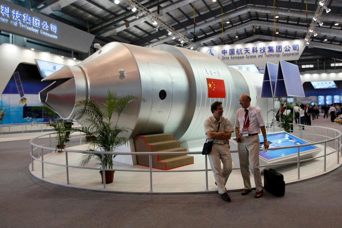 In this Nov. 16, 2010, file photo, visitors sit beside a model of China’s Tiangong-1 space station at the  eighth China International Aviation and Aerospace Exhibition in Zhuhai in southern China’s Guangdong province. (Kin Cheung / Associated Press)