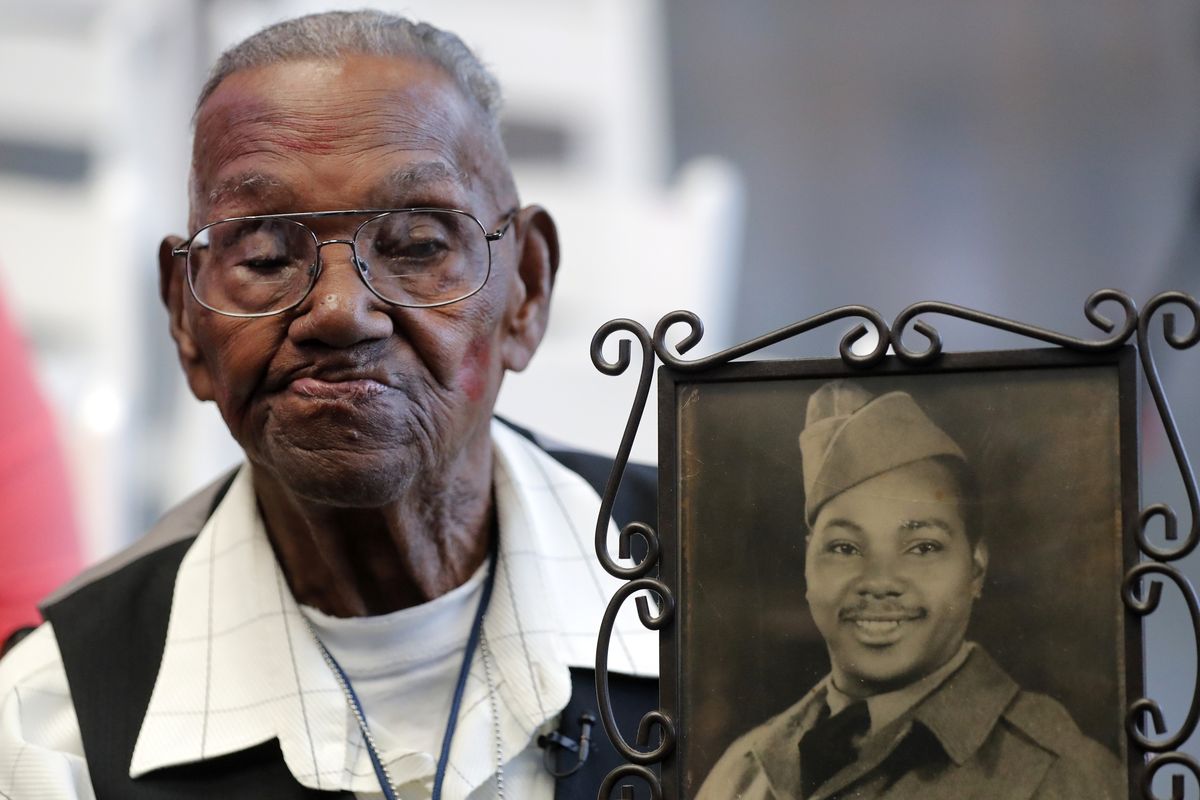 FILE - In this Sept. 12, 2019 file photo, World War II veteran Lawrence Brooks holds a photo of him taken in 1943, as he celebrates his 110th birthday at the National World War II Museum in New Orleans. Brooks celebrated his 112th birthday, Sunday, Sept. 12, 2021 with a drive-by party at his New Orleans home hosted by the National War War II Museum. Drafted in 1940, Brooks was a private in the Army’s mostly Black 91st Engineer Battalion.  (Gerald Herbert)