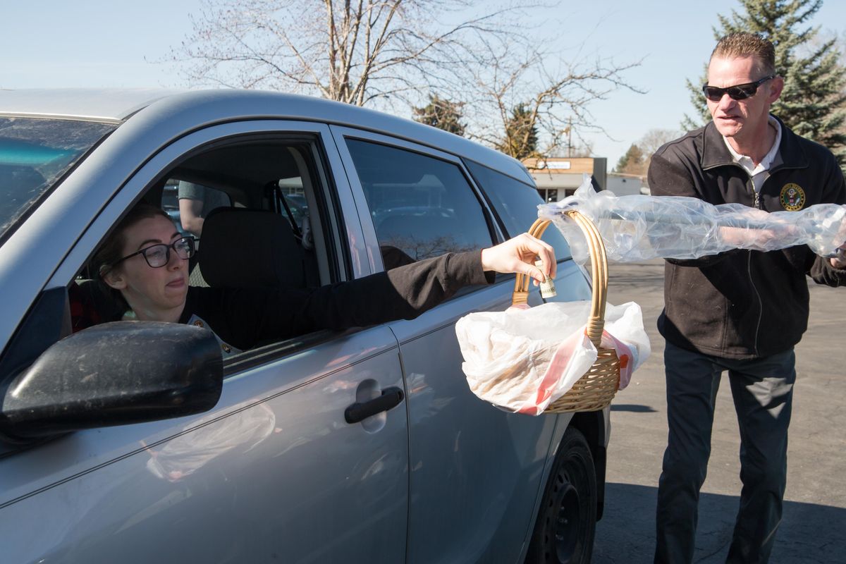 Courtney Durrant drops money into the collection basket, without touching the basket, handled by Craig Rudder during Shadle Park Presbyterian Church