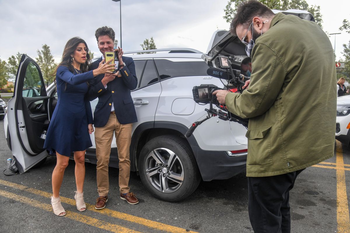 Danielle Lam, left, and Howie Guja, of the Publishers Clearing House Prize Patrol, take of picture of a Champagne bottle in the Safeway parking lot on Market Street before heading out to award a $1 million dollar prize to William McGunagle of Spokane, Friday, April 30, 2021.  (DAN PELLE/THE SPOKESMAN-REVIEW)