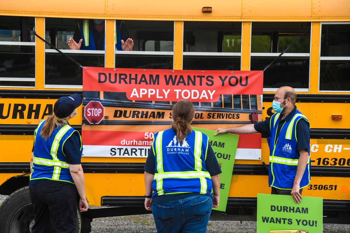 Durham School Services drivers hang a ‘help wanted’ sign on a bus at Joe Albi Stadium on July 23, 2020.  (DAN PELLE/THE SPOKESMAN-REVIEW)