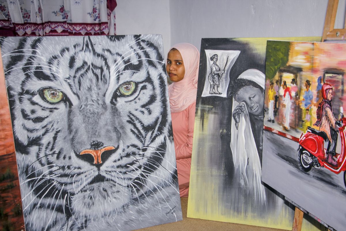 Somali artist Sana Ashraf Sharif Muhsin, 21, sits with some of her paintings Oct. 15 at her home in the capital Mogadishu, Somalia. “Our paintings talk to the people,” Ashraf Sharif Muhsin said.  (Farah Abdi Warsameh)