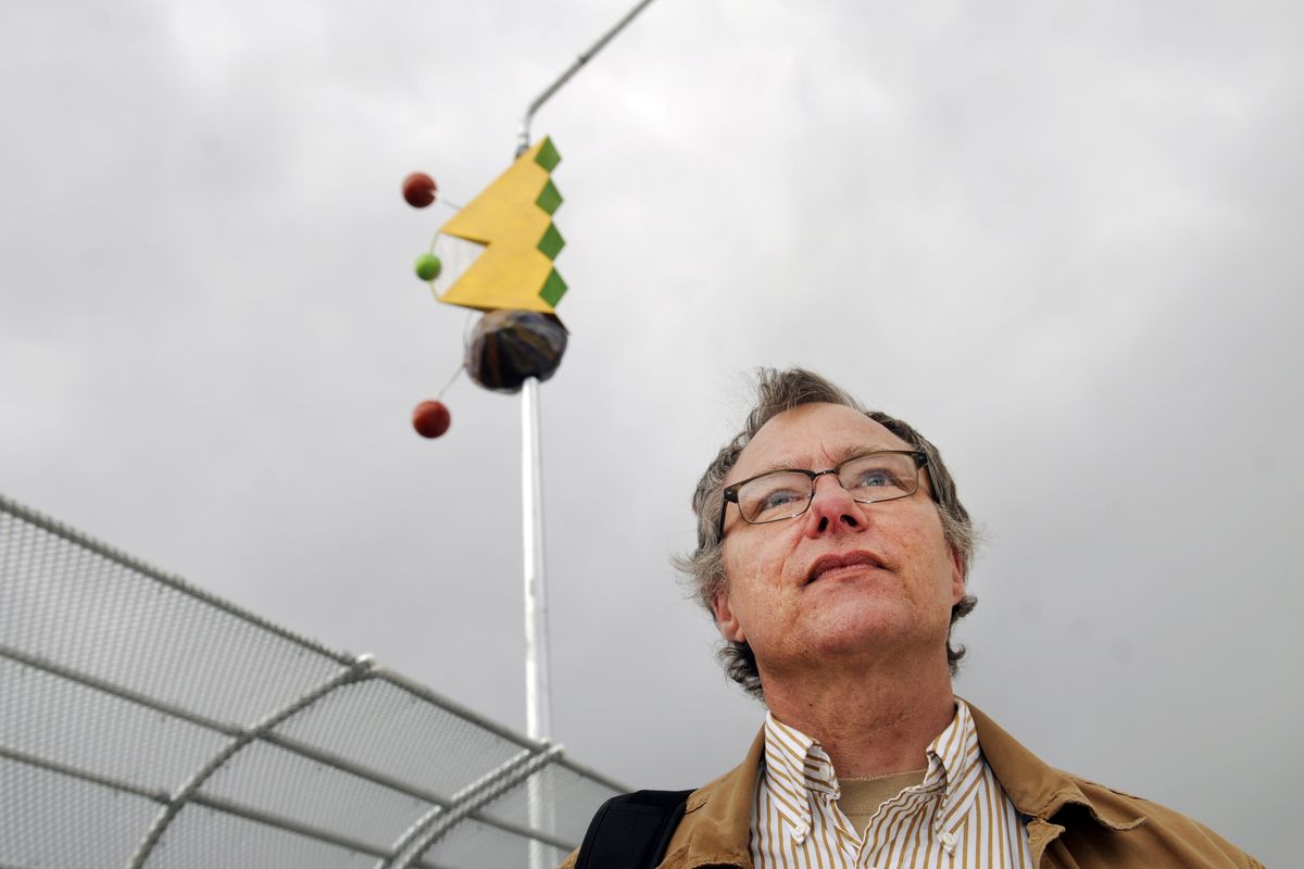 Artist Roger Ralston stands below one of the wind vanes he designed for the new Freya Street bridge  Thursday. The public art project consists of three whimsical wind vanes hanging on light poles along the bridge. (PHOTO by JESSE TINSLEY)