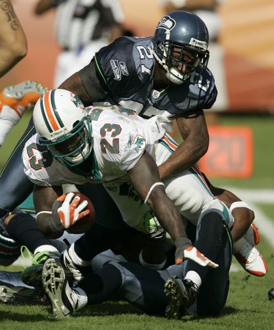 Dolphins running back Ronnie Brown (23) is taken down by  the Seahawks’  Jordan Babineaux, top, and  Josh Wilson.   (Associated Press / The Spokesman-Review)