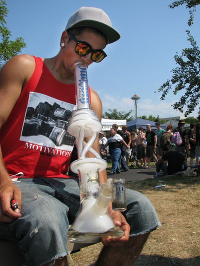 A Bothell, Wash., man smokes marijuana from a glass bong at the opening day of the pro-marijuana rally Hempfest in Seattle last summer. Tens of thousands are expected to attend Hempfest this weekend. (Associated Press)
