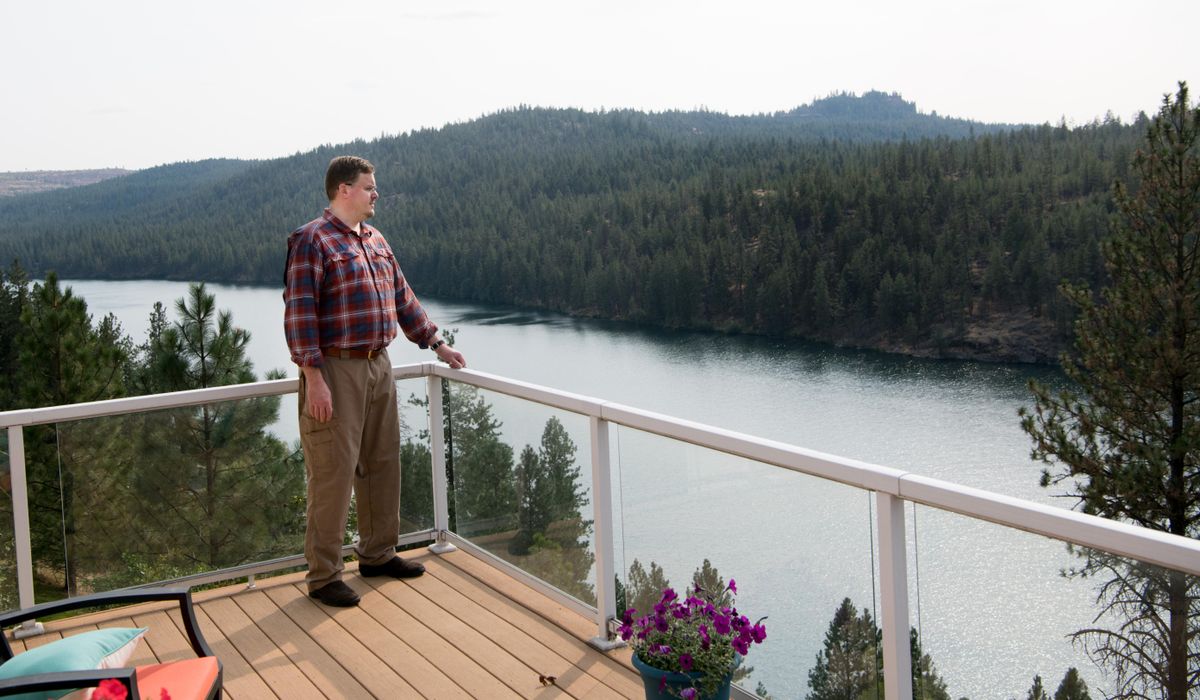 Andrew Dill, poses for a photo on the deck of his waterfront home he