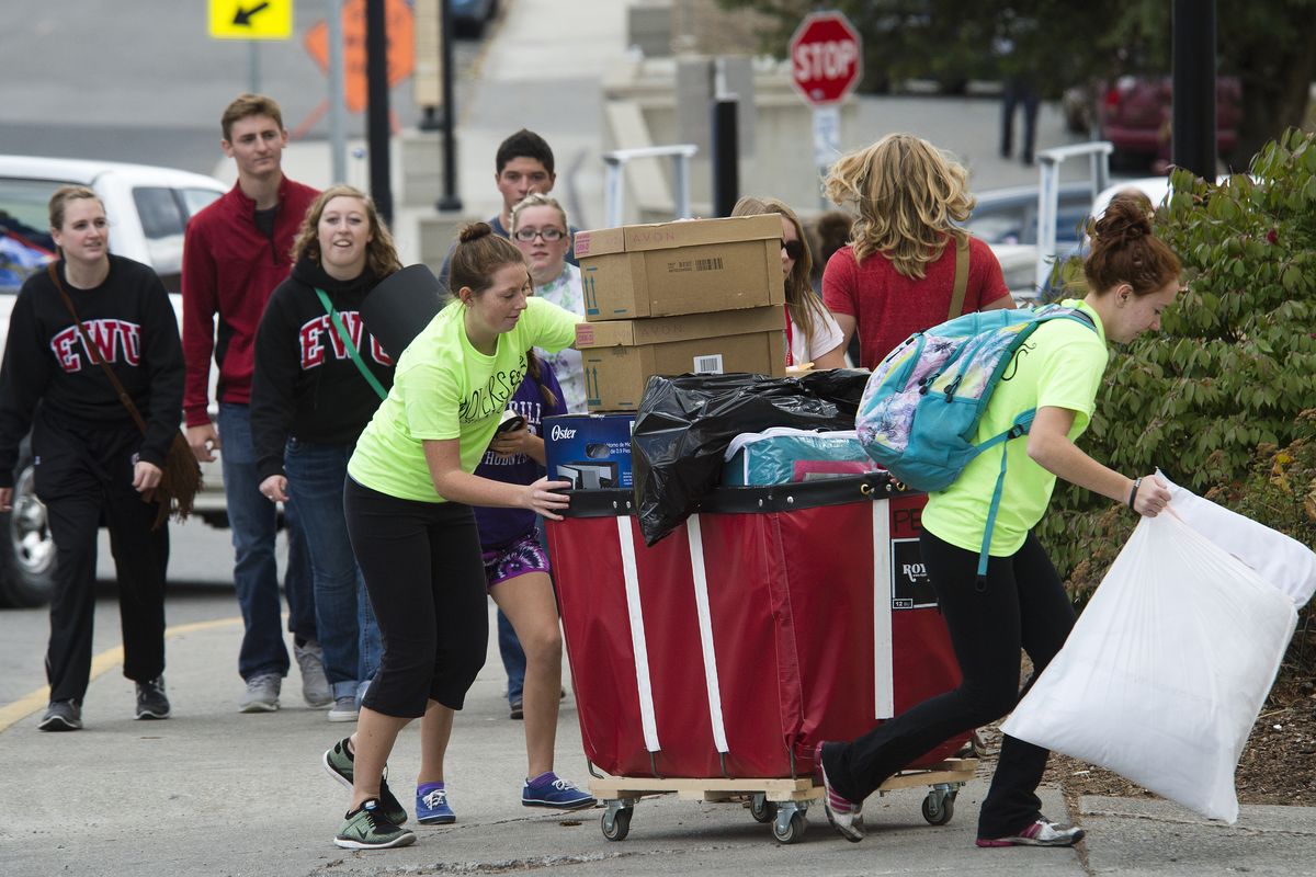 Eastern Washington University students help a freshman transport a cart full of belongings into Pearce Hall in Cheney on Friday. (Dan Pelle)