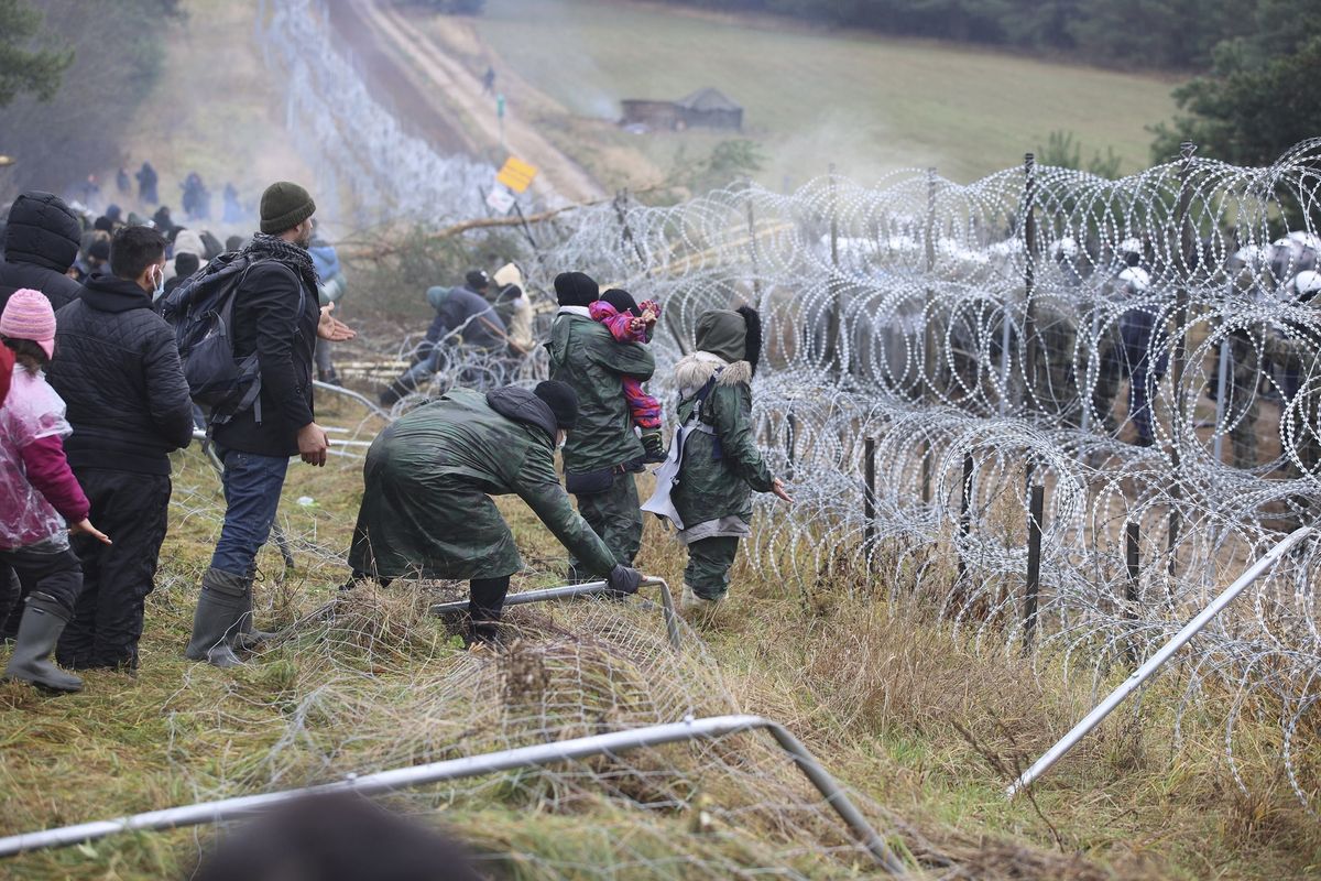 Migrants break down the fence as they gather at the Belarus-Poland border near Grodno, Belarus, on Monday. Poland increased security at its border with Belarus after a large group of migrants appeared to be congregating at a crossing point, officials said Monday.  (Leonid Shcheglov)