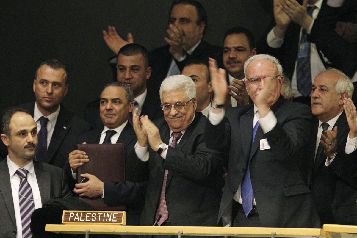 Members of the Palestinian delegation react as they surround Palestinian President Mahmoud Abbas, center, applauding, during a meeting of the United Nations General Assembly after a vote on a resolution on the issue of upgrading the Palestinian Authority