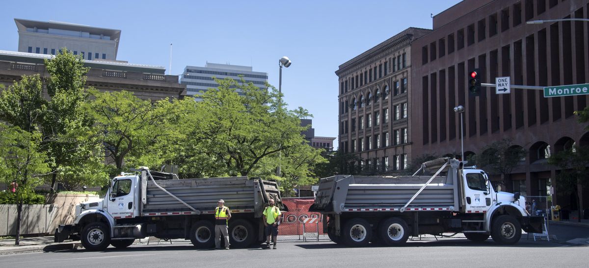 City of Spokane Street Department dump trucks, filled with ground-up asphalt, block the corner of Riverside Avenue and Monroe Street during Hoopfest 2017. (Dan Pelle / The Spokesman-Review)