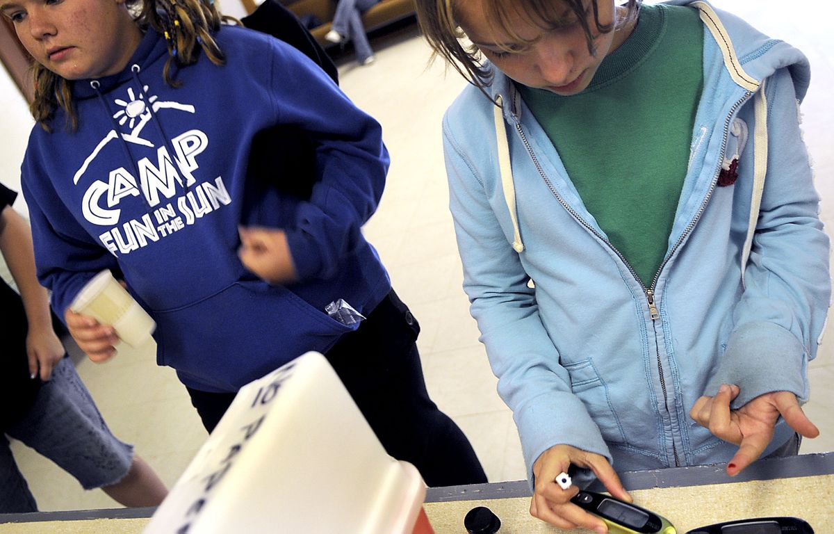 Campers Kimberly Loranger, left, 12, of Ephrata, Wash., and Jodie Scalf, 12, right, of Millwood, test their blood. (Kathy Plonka / The Spokesman-Review)