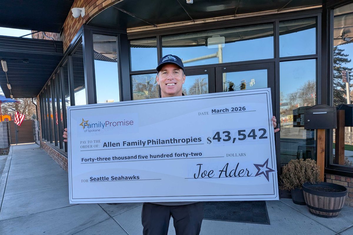 Family Promise of Spokane CEO Joe Ader poses with a large check featuring the organization’s bid to purchase the Seattle Seahawks.  (Courtesy)