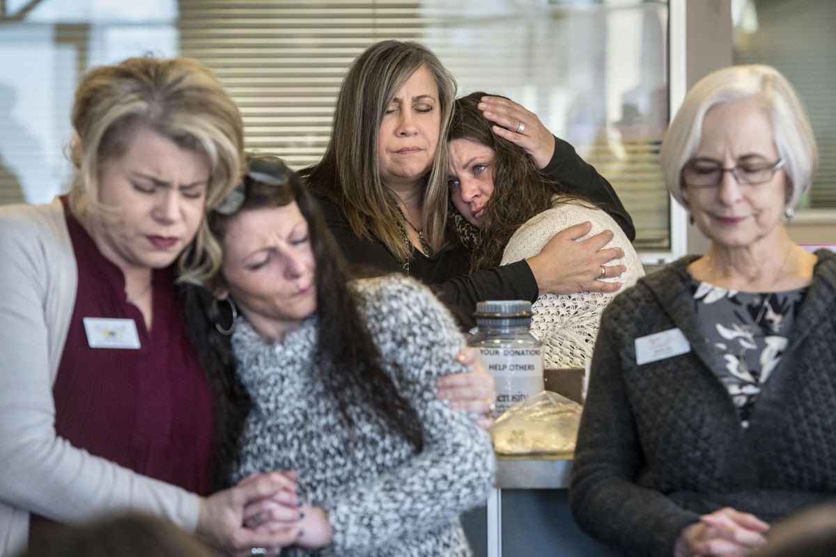 Christ Clinic front office lead Sharon Bryant-Butcher, center left, embraces an emotional community health worker Stephanie Beckham, during a morning prayer gathering of 30 people, Feb. 2, 2017, in the clinic’s lobby. The free medical clinic is closing down after more than 20 years due to budgetary and staffing issues. Kim Kelly, of Christ Kitchen, hugs Alisha Miller and referral specialist Marilee Meeks prays at right. (Dan Pelle / The Spokesman-Review)